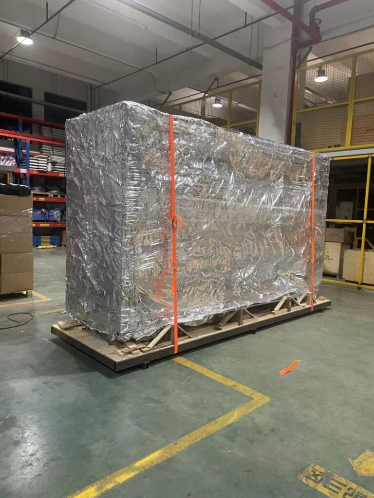 Large industrial mold fully wrapped in anti-rust protective film and secured on a wooden pallet inside a warehouse, ready for long-term export transport.