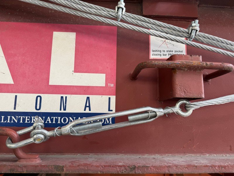 Detailed shot of a turnbuckle tensioning device connected to a stake pocket on a TAL container, emphasizing the need for verified execution and proper tensioning in cargo securing.