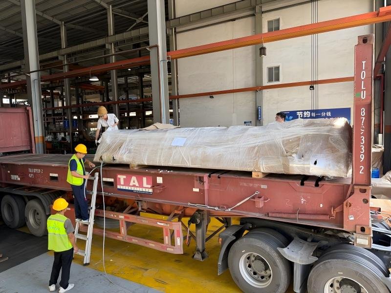 Workers securing oversized equipment on a flat rack with correct lashing techniques