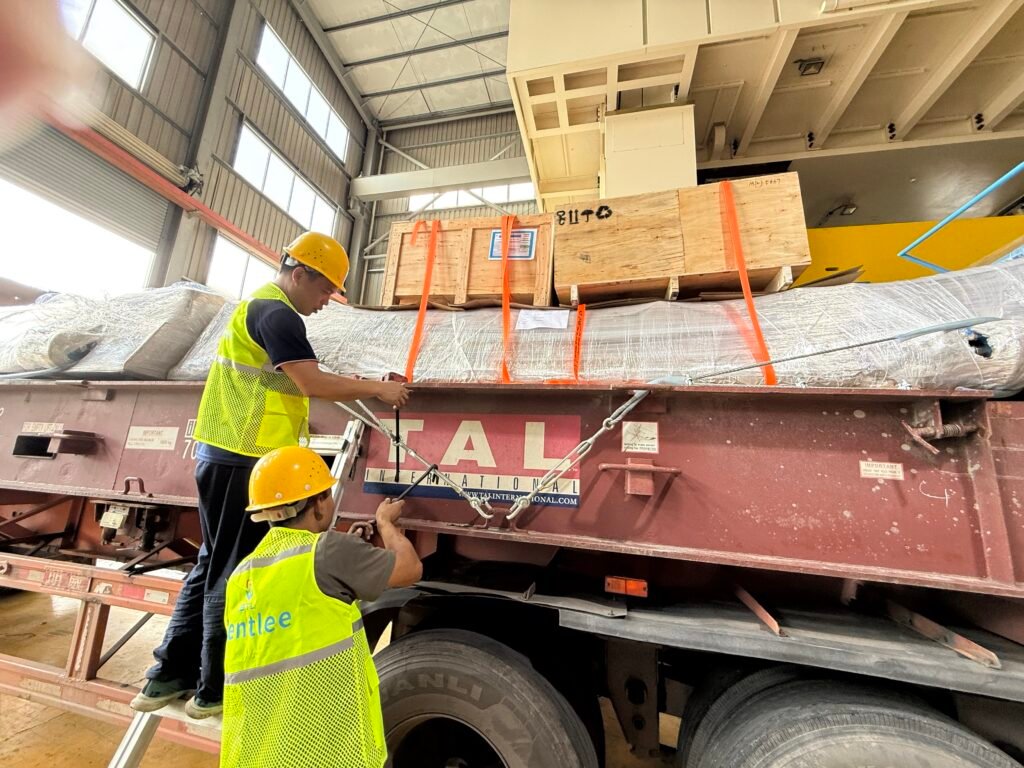 Worker adjusting orange straps and wire ropes on an Open Top container with side walls and tarpaulin roof