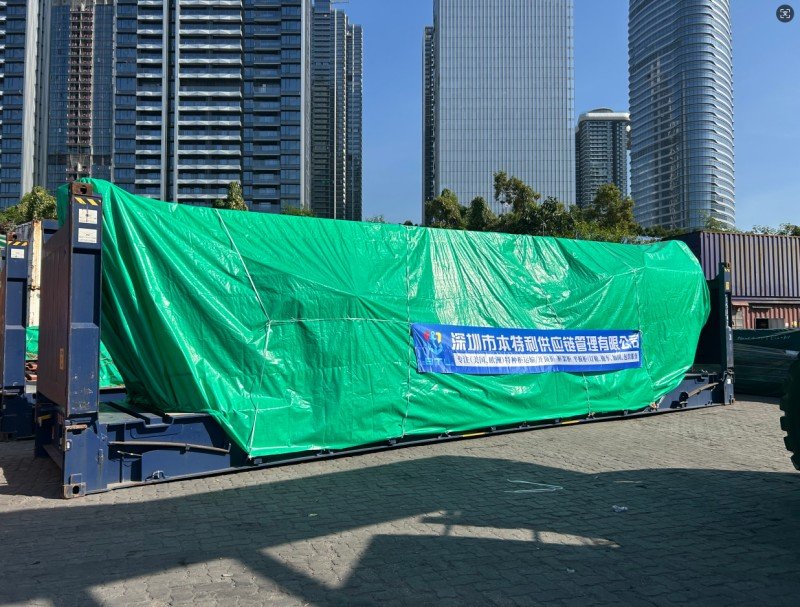 Large out-of-gauge cargo covered with green tarpaulin in an urban setting, illustrating the need for accurate OOG declaration forms and terminal-specific approval documents to prevent booking rejection or port detention charges