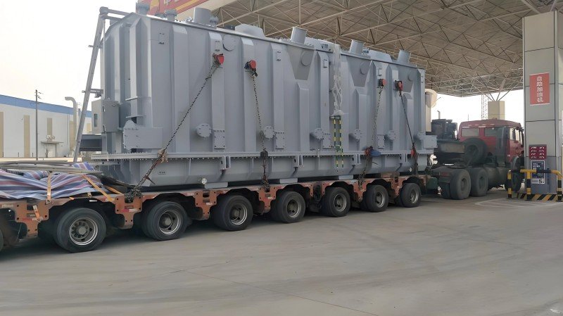 Massive gray industrial machinery loaded on a multi-axle flatbed trailer, showcasing breakbulk shipping for extremely heavy and oversized cargo that requires specialized logistics solutions.