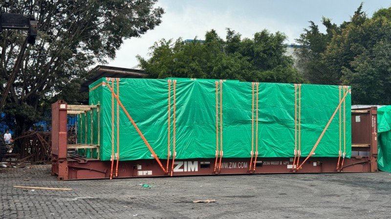 Large machinery covered with green tarp on ZIM framework flat rack (ZCSU 863222) — secured with orange lashing straps; no side walls, ideal for wide cargo.
