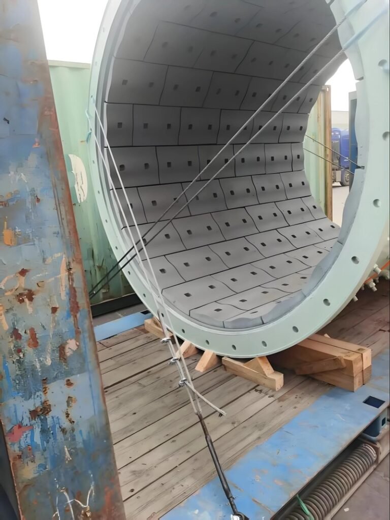 Detailed view of a large industrial cylinder interior showing wire lashing systems attached to the flat rack container's wooden dunnage and steel frame, demonstrating weight distribution and stability measures for oversized cargo transport.
