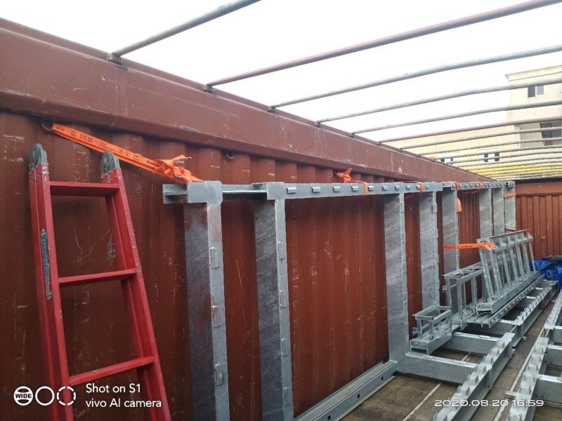 Metal framework secured with orange lashing straps inside an open top container to prevent shifting during transit