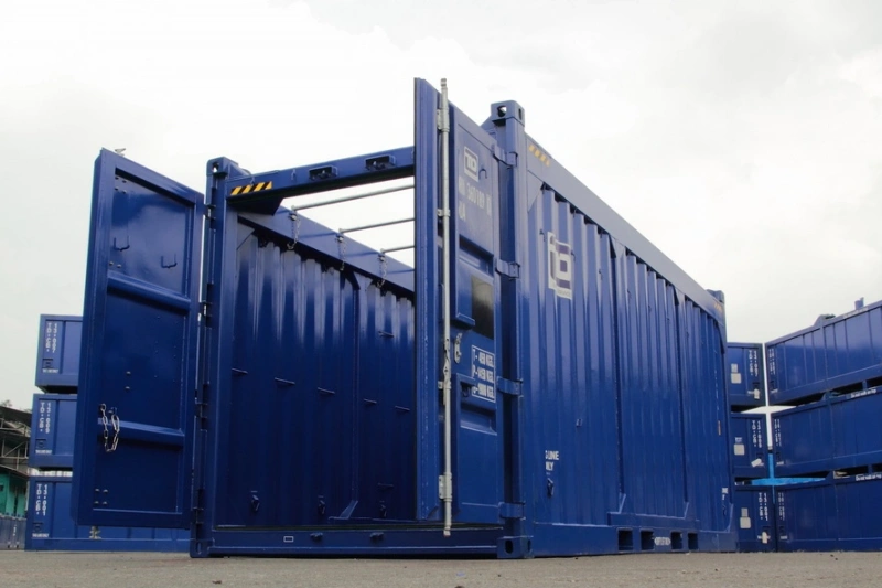 Blue open top shipping container with removable tarpaulin roof used for lifting oversized machinery from the top