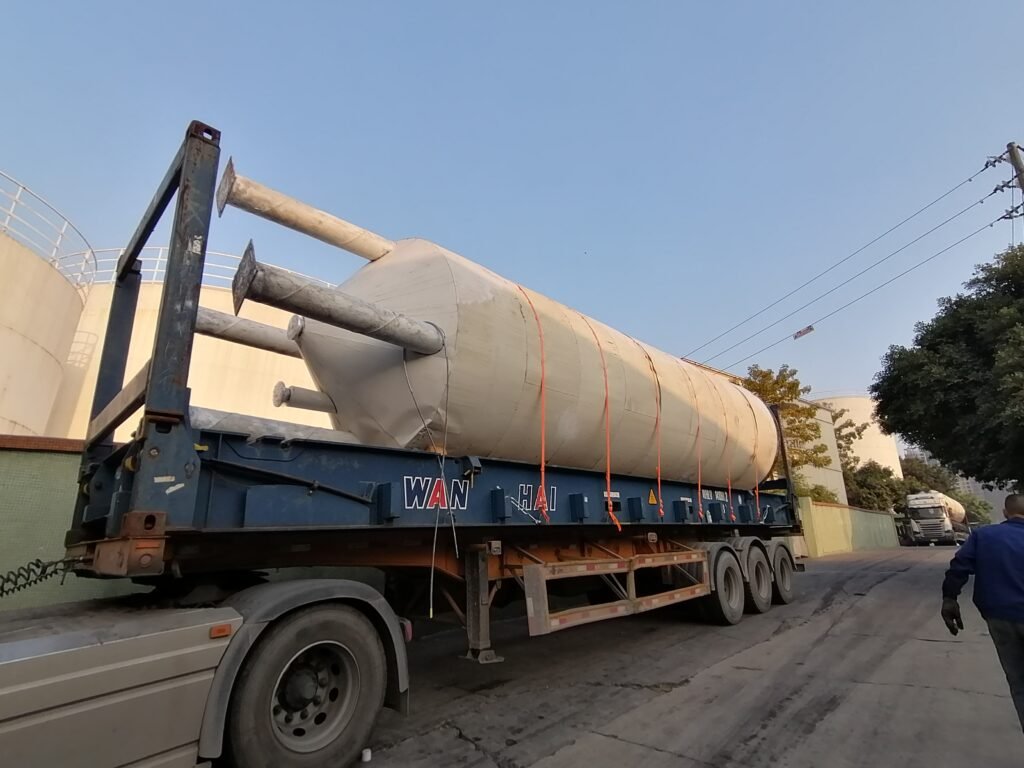 Large cylindrical tank with protruding pipes secured on a WAN HAI flat rack trailer ready for OOG shipment