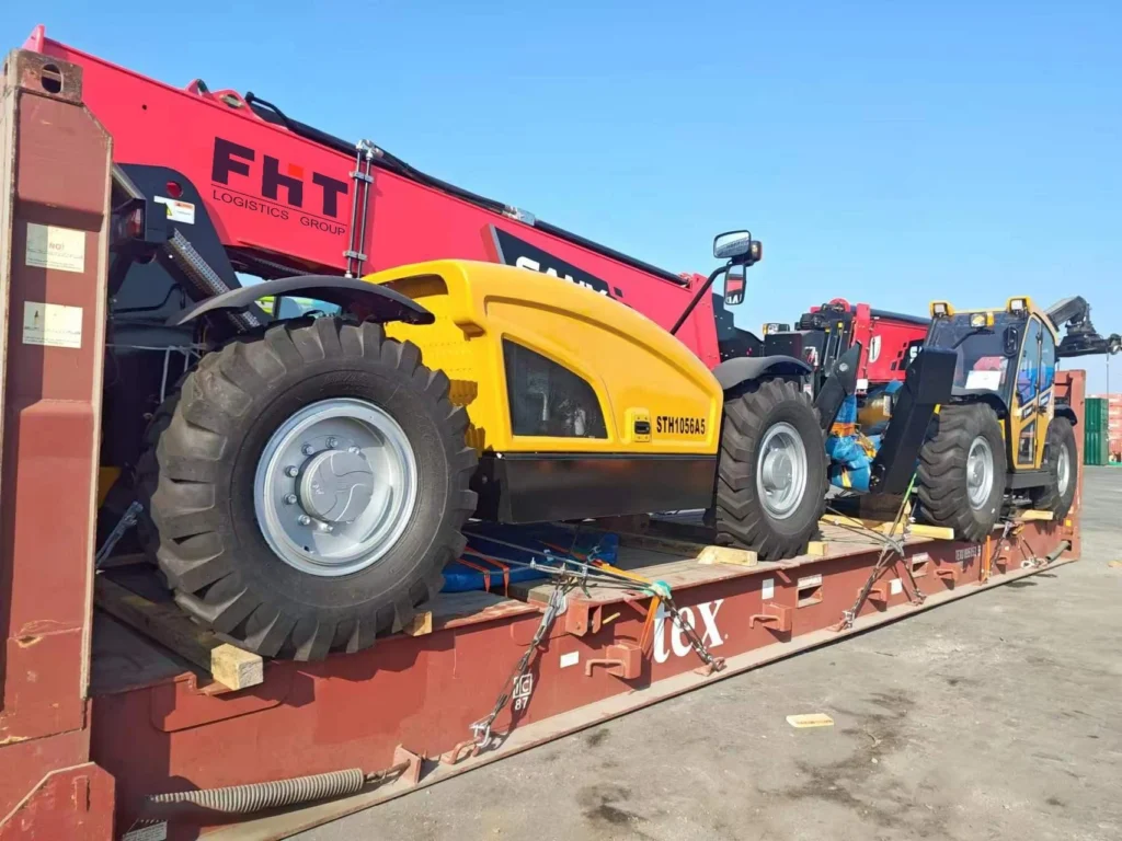 A yellow and red Sany telehandler (model STH1056A5) is positioned on a reddish-brown flat rack container in a port yard, secured with chains and wooden blocks.