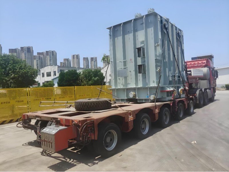 Power transformer securely loaded on multi-axle lowbed trailer with chain lashing and protective padding during inland transport