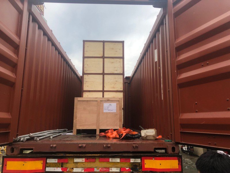 Interior view of an open top container showing stacked wooden crates, illustrating proper weight distribution and center of gravity (COG) alignment for stable sea transport.