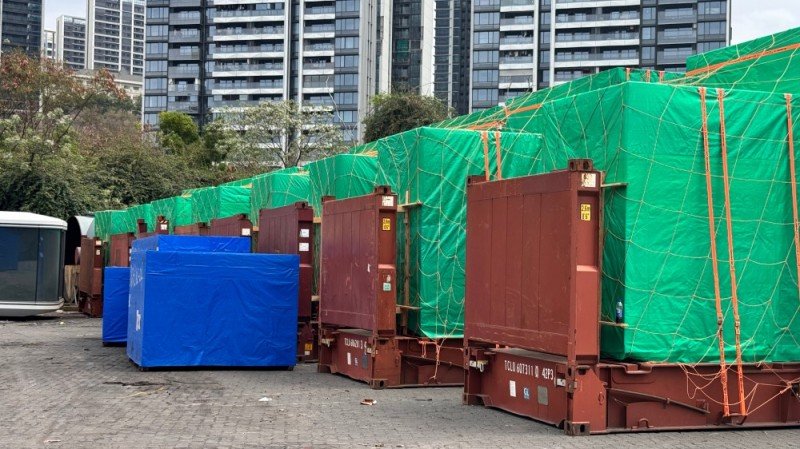 Rows of flat rack and open top containers (green/blue tarps, TCLU/ZIM IDs) staged at logistics yard—secured for international oversized freight transport.