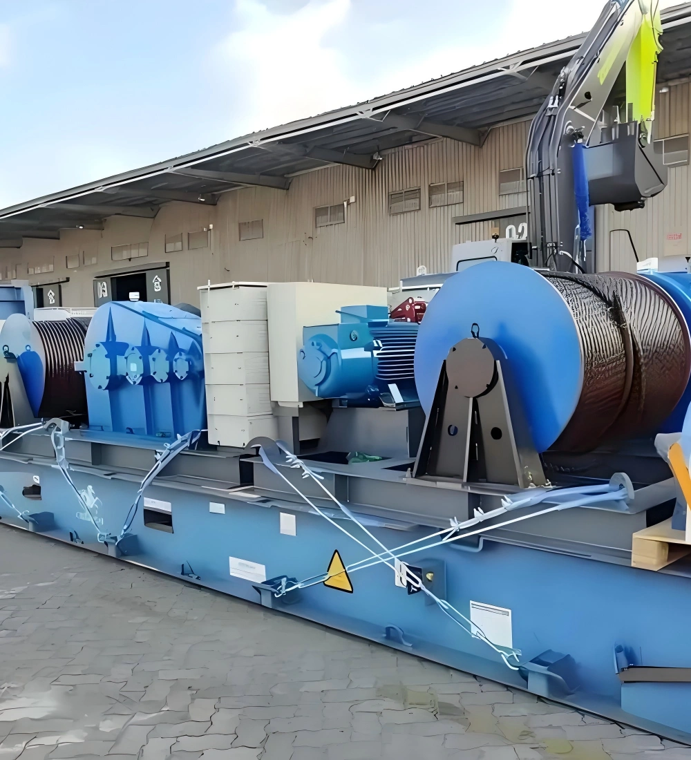 Blue mining support equipment including cable drums winches and electric motors mounted on steel skid frame and secured with synthetic lashing straps