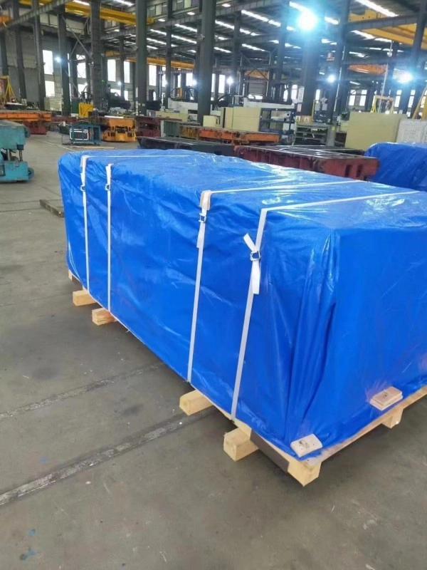 Industrial cargo on wooden pallet covered with blue waterproof tarp and secured with white tension straps for pre-vacuum moisture protection in warehouse