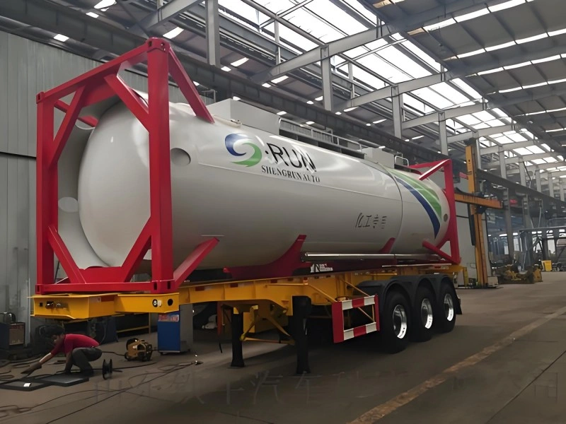 A large white chemical tank container mounted on a yellow trailer with a red frame, labeled "SHENGRUN AUTO" and Chinese characters indicating its use for chemical transport. The setup is inside a warehouse with industrial equipment visible.