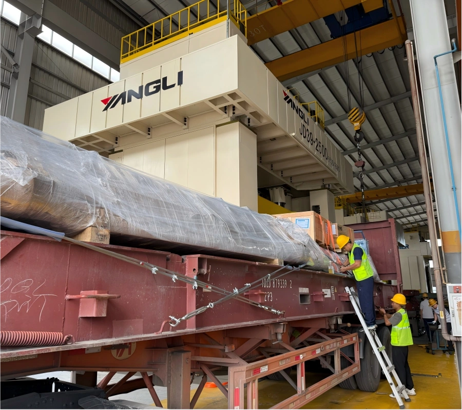 Oversized cylindrical machinery component lifted by overhead crane and positioned on flat rack trailer under YANGLI gantry system for safe loading