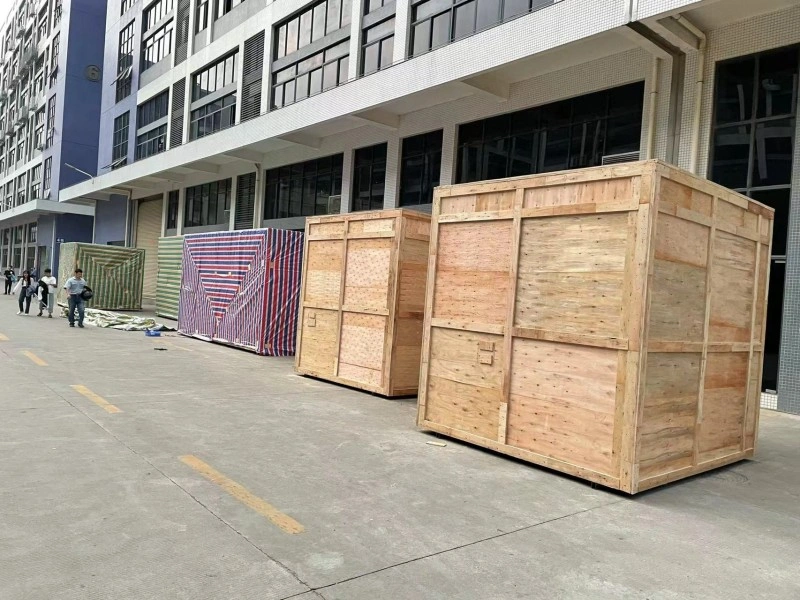 Large, custom-built wooden shipping crates sitting outside a warehouse facility, ready for loading, showcasing reinforced framing designed for heavy and oversized industrial cargo.