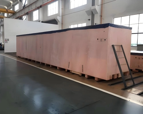 Extra long wooden case painted pink on skids with protective tarp cover and access ladder for factory relocation project cargo