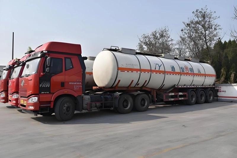 A red FAW 8x4 heavy-duty truck with a large white tanker trailer. The trailer is marked with orange and white hazard stripes and Chinese characters for "Corrosive Substance Logistics," indicating its use for transporting dangerous goods.