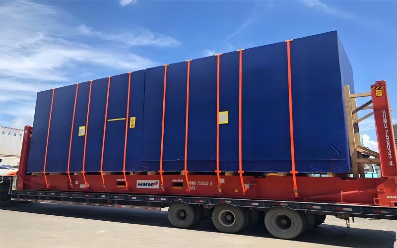 Long cargo overhanging sides on HMM flat rack, secured with orange straps — ideal only when width > 2.35m.