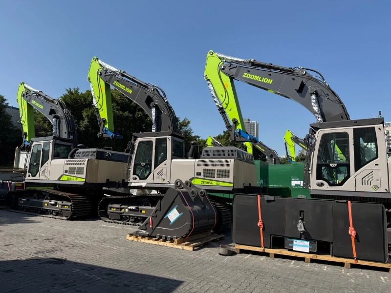 A row of Zoomlion excavators parked in a yard with detached buckets and counterweights neatly arranged on wooden pallets in the foreground, prepared for container loading.