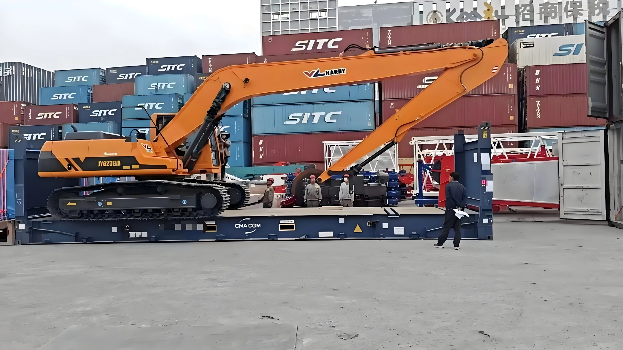 Orange HARDY JYG23ELD excavator secured on a CMA CGM flat rack container at port yard, ready for OOG shipment