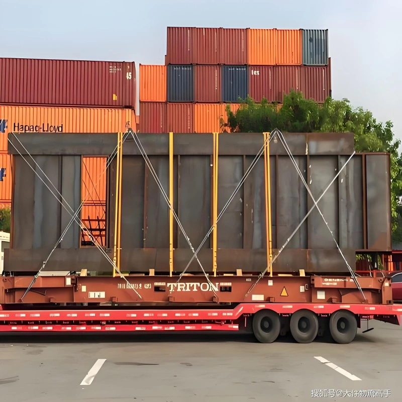 A large, heavy industrial module is secured on a TRITON flat rack container using yellow vertical supports and diagonal steel lashing straps, with stacked Hapag-Lloyd shipping containers in the background at a port logistics yard.