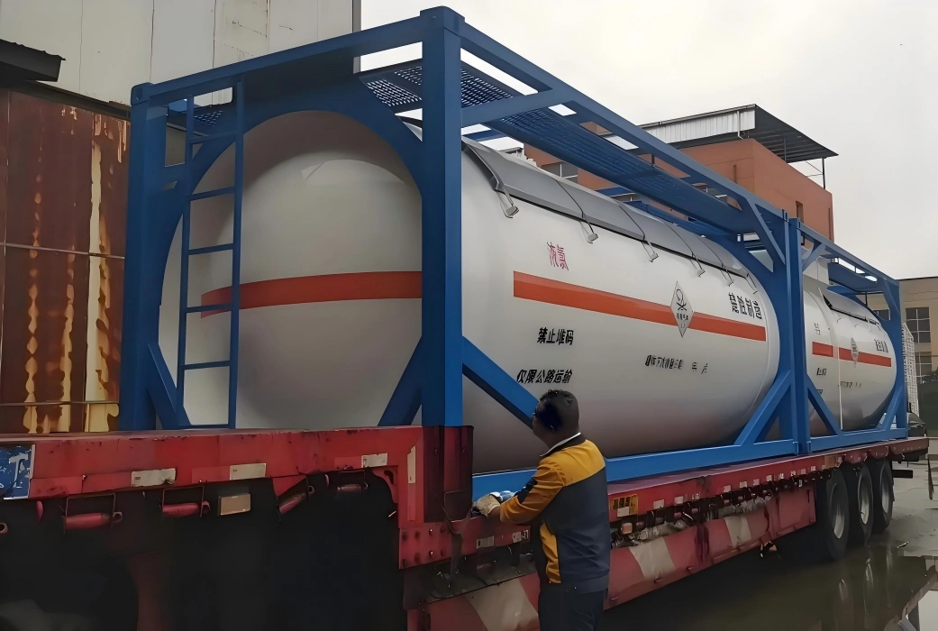 ISO tank container frame transporting white hazardous liquid tank with red band UN hazard markings and Chinese safety labels being secured on flatbed trailer