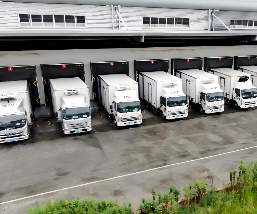Fleet of white JAC refrigerated trucks parked at designated loading bays for synchronized cold chain dispatch operations at distribution center