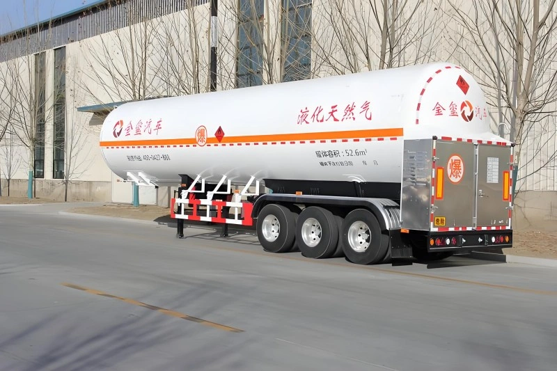 A white LNG tanker trailer with a cylindrical tank, marked with orange hazard stripes and Chinese characters specifying its use for liquefied natural gas. The trailer is shown on a paved road with a building and trees in the background.