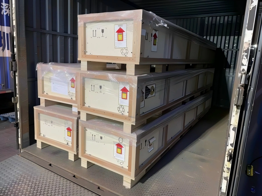 Stacked wooden cases inside shipping container with standardized handling labels including fragile, moisture sensitive and orientation marks