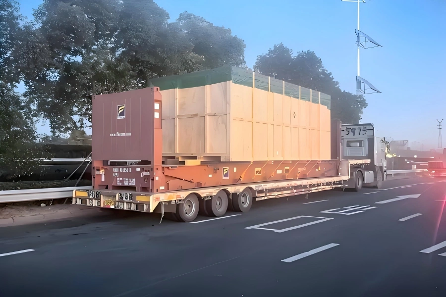 Oversized wooden crate transported on multi axle lowbed trailer during highway transit for heavy industrial project cargo delivery