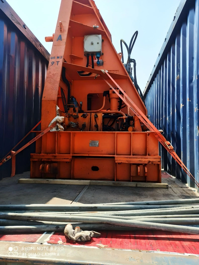 9-ton industrial machine secured with orange lashing straps and wooden dunnage inside an open top container for safe transit