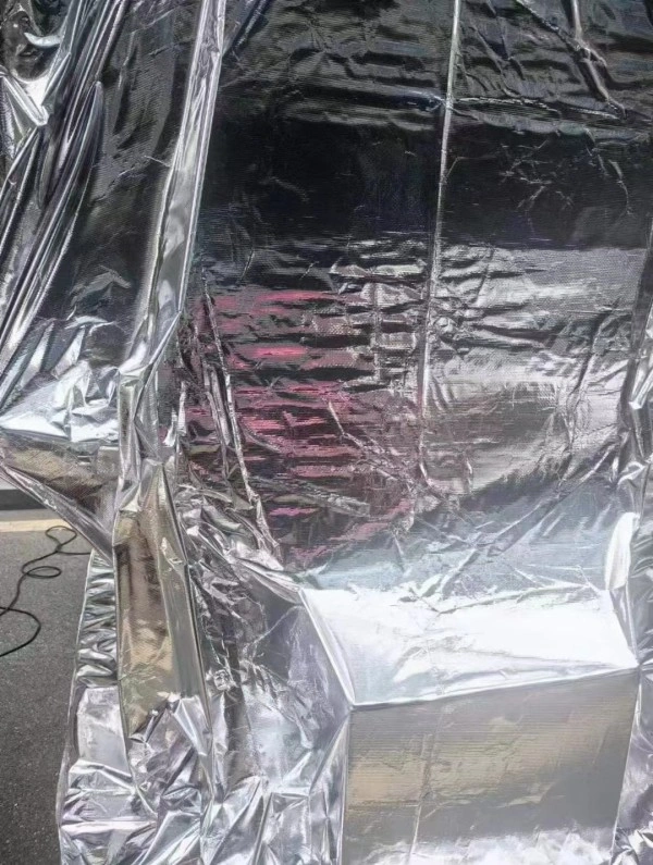 Close up of vacuum packed cargo wrapped in silver metallized moisture barrier film with visible seal lines for corrosion prevention during export transit