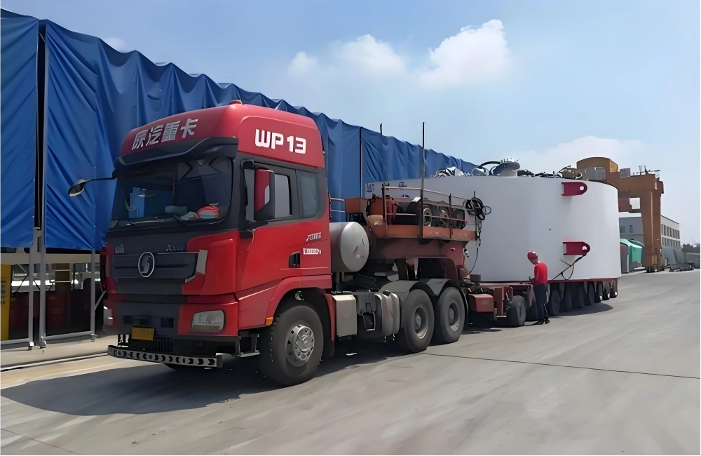 Red Sinotruk WP13 tractor unit hauling white mining plant module on extended lowbed trailer at logistics yard for mine expansion project