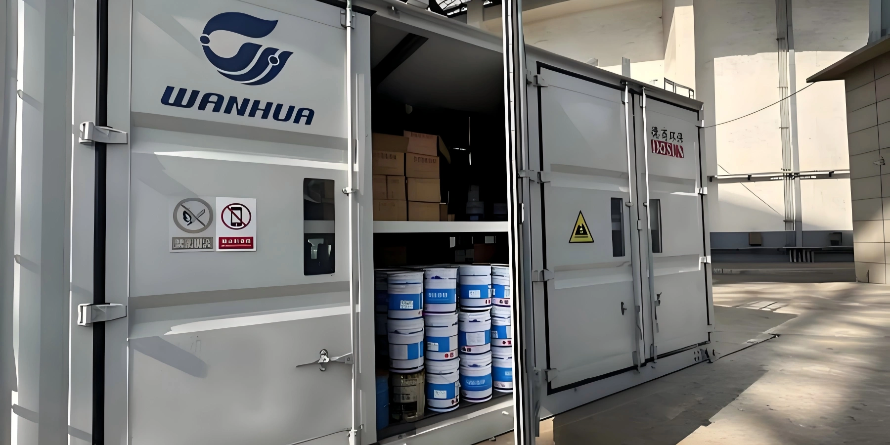 White insulated container branded WANHUA with open doors showing stacked chemical barrels and hazard warning signs including no smoking and no mobile phone