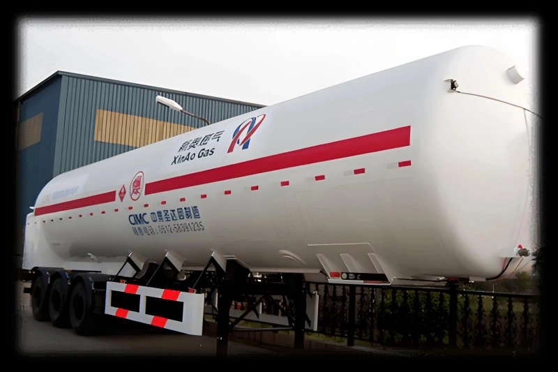 White LNG tanker trailer with red stripe and "XieAo Gas" branding, manufactured by CIMC, parked outside an industrial facility with visible safety markings and contact information