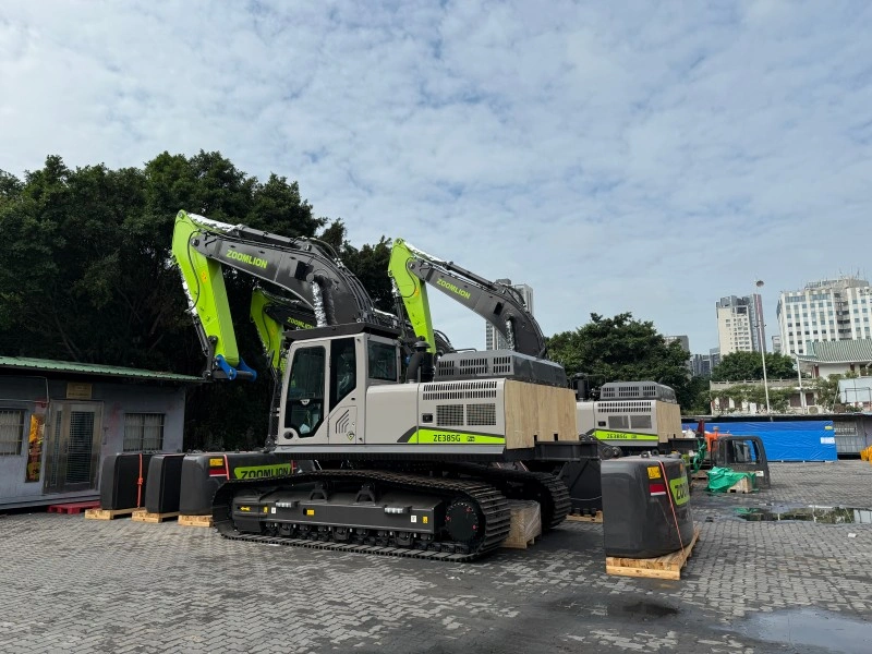 A large Zoomlion ZE385G excavator with a green and grey color scheme is parked on a paved lot, prepared for transport.