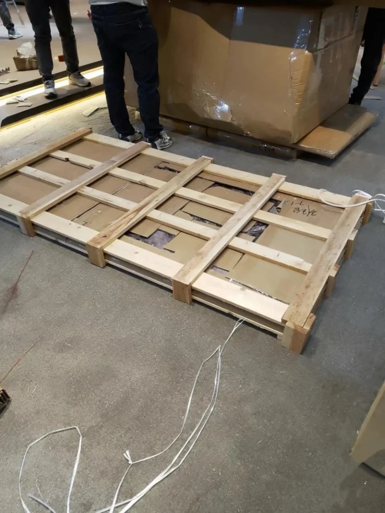 Custom-built wooden crate framework securing yellow industrial components with protective padding and export-compliant markings