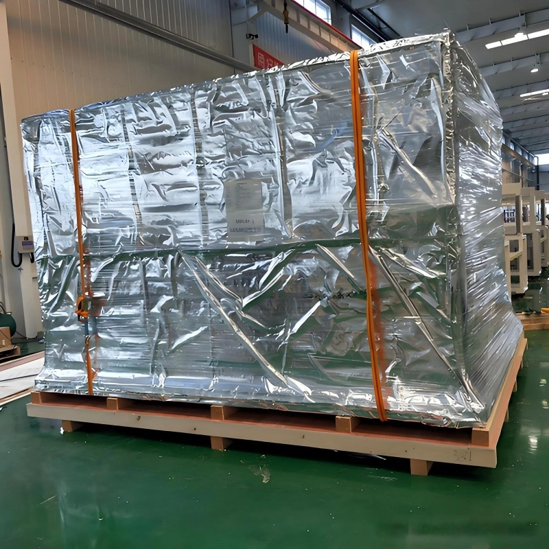 A fully wrapped industrial machine secured with orange straps on a skid, highlighting the integration of vacuum sealing and external reinforcement for export readiness.