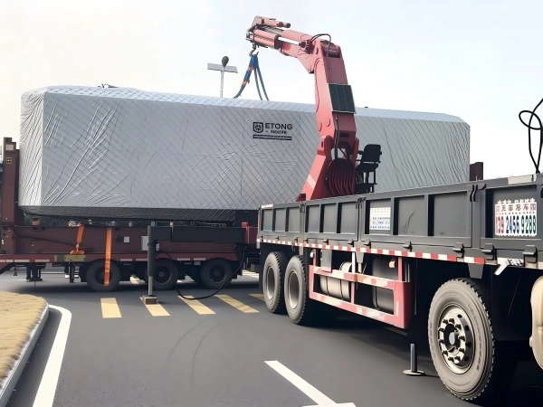 A crane lifting a fully wrapped space capsule cabin onto a transport trailer, demonstrating the heavy lifting required for OOG cargo