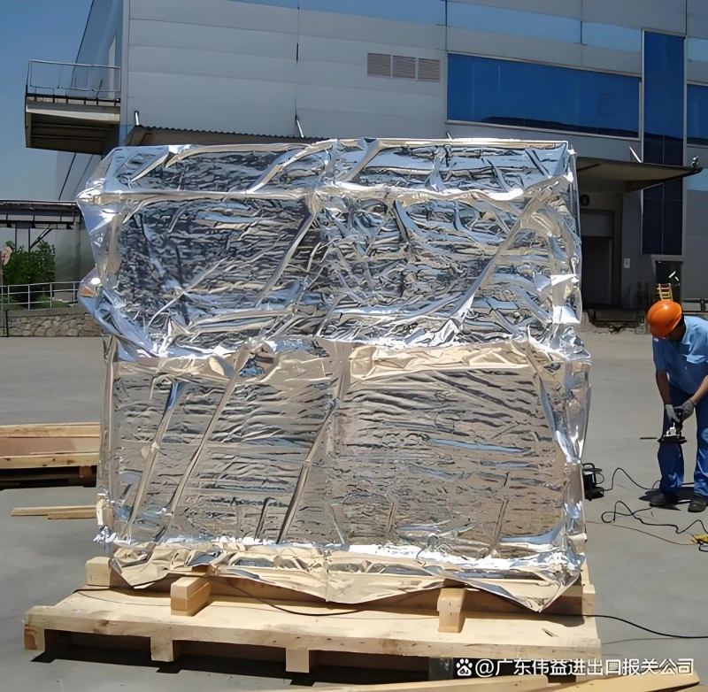 Worker sealing a large metal equipment with silver aluminum vacuum packaging material outdoors, ensuring waterproof and anti-corrosion protection for international shipping.