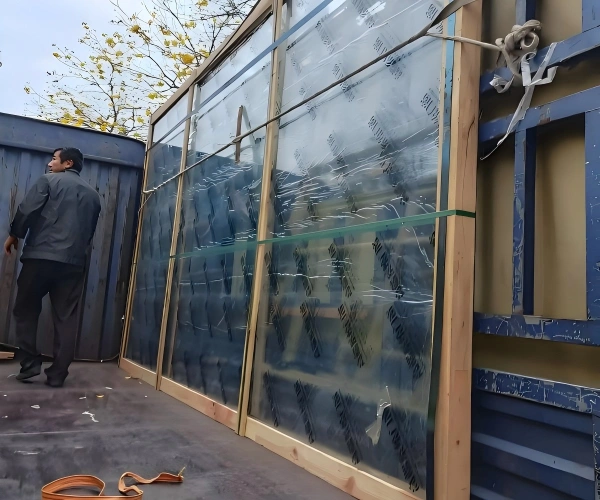 Close-up view of glass panels protected by custom wooden framing and contact-point padding to prevent edge damage during transit.