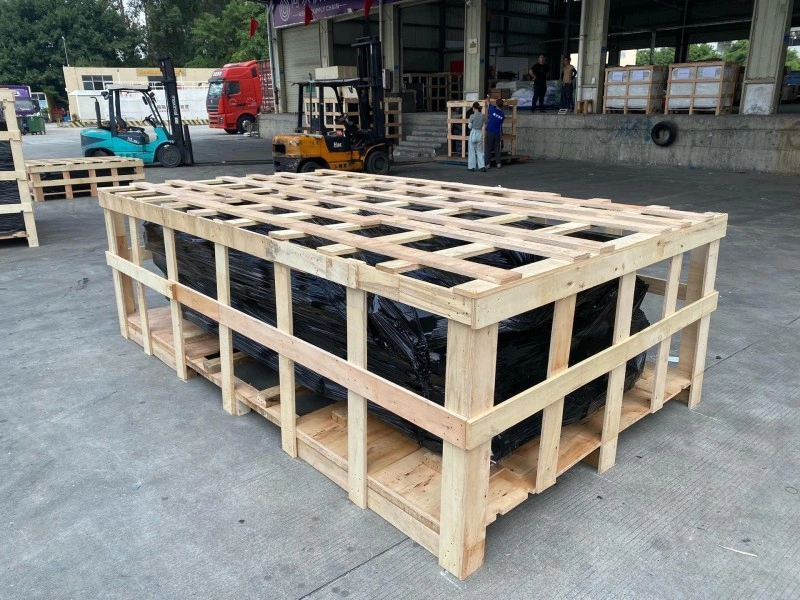 Large wooden crate with reinforced bracing and black-wrapped industrial equipment inside, designed for secure international shipping under ISPM 15 standards