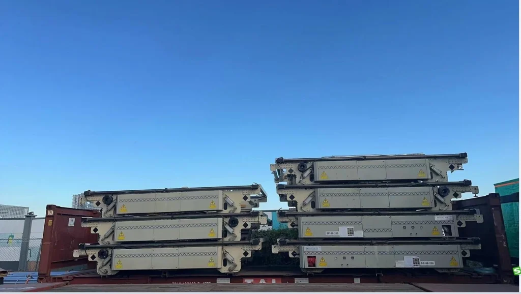 Two vertical stacks of beige industrial presses, each labeled “MING WEI SP-08-250”, loaded side-by-side on a red flat rack container at an outdoor logistics terminal under bright daylight.