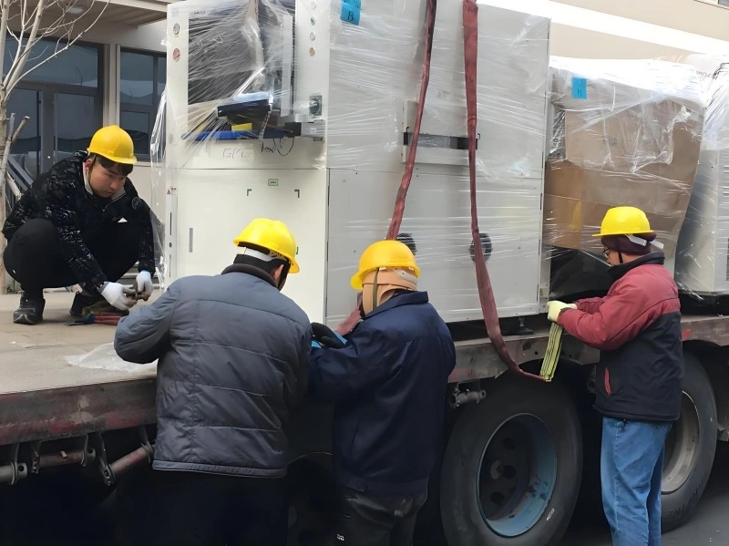 Movers performing final safety checks and adjusting securing straps on loaded machinery, verifying readiness for transport in a professional factory move.