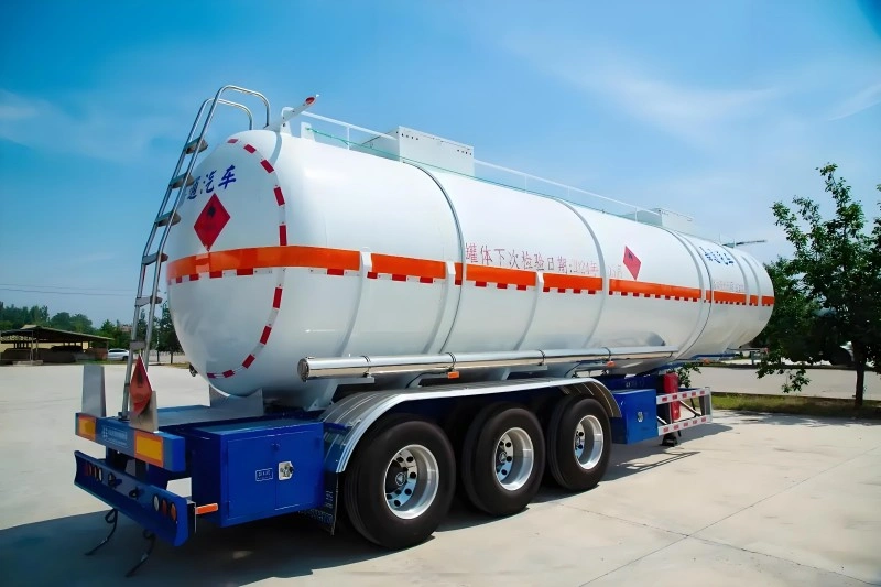 A white tanker trailer with orange hazard markings, designed for transporting flammable liquids