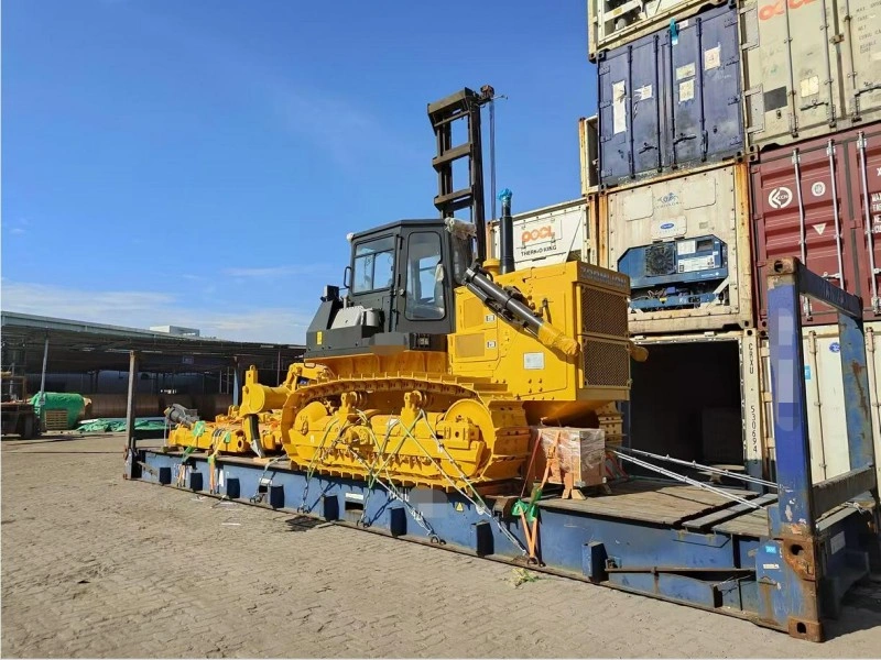 Frontal perspective of a yellow bulldozer loaded on a flat rack container with visible tie-downs, highlighting the execution and monitoring stage of large-scale logistics.