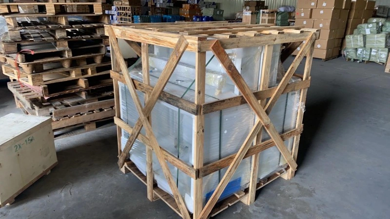 Large industrial wooden crate with distinctive X-shaped cross bracing on the sides, containing white-wrapped goods, optimized for stacking and impact resistance in logistics.