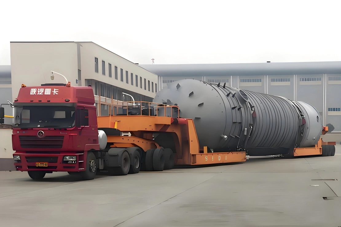 Red truck tractor hauling a massive pressure vessel on an orange low-bed trailer, showcasing heavy equipment transport capabilities in China.