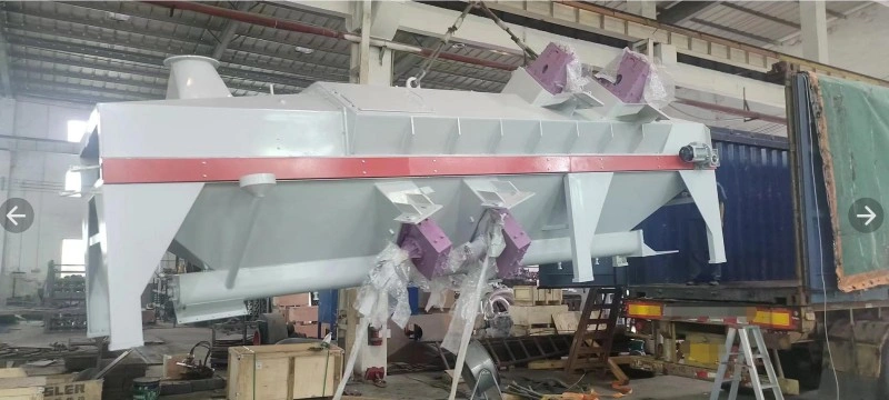 A yellow and green hydraulic press machine is firmly anchored inside a reddish-brown shipping container using multiple orange ratchet straps and wooden blocking to prevent movement.
